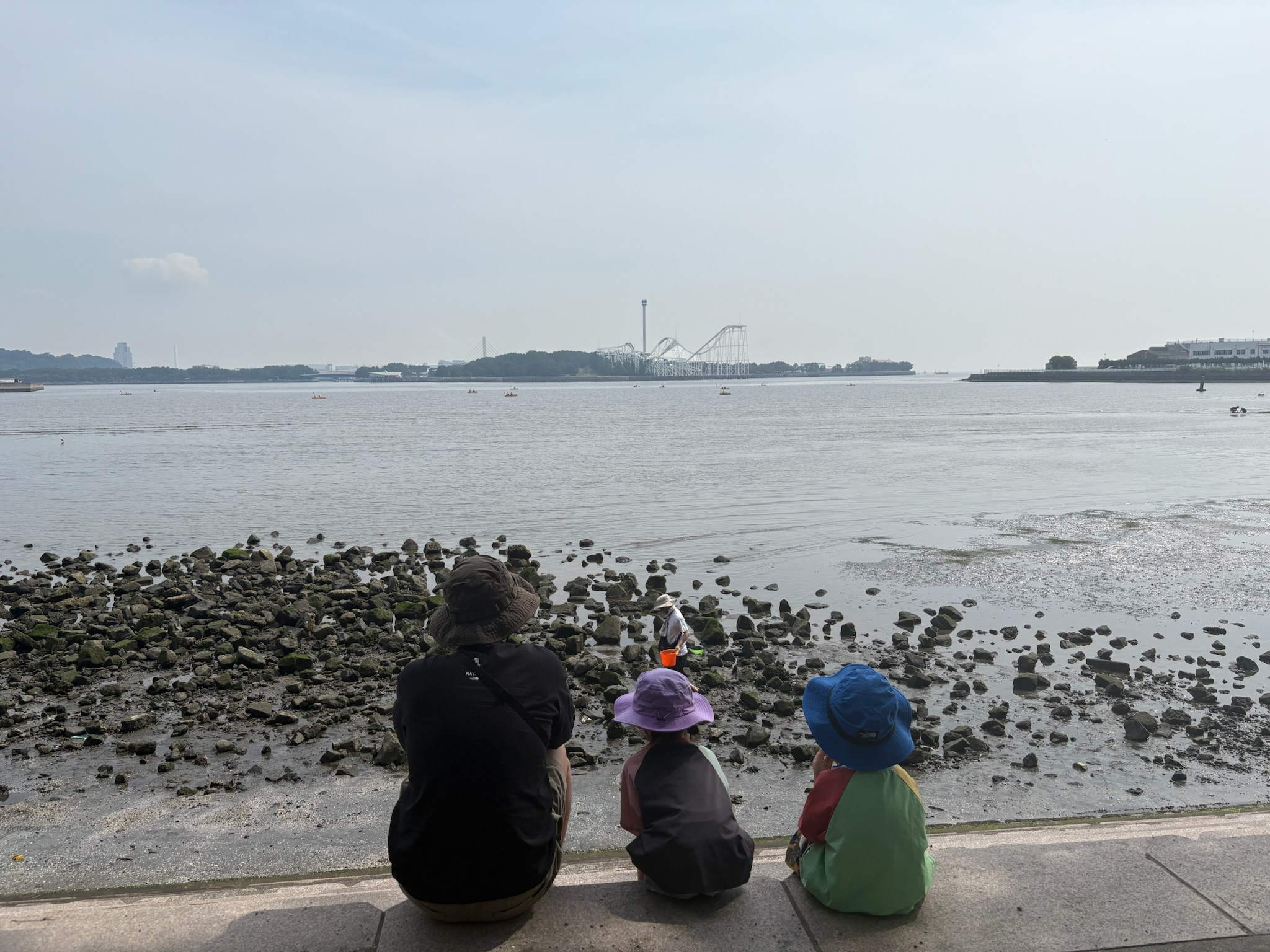 野島公園で潮干狩りをする親子。対岸に八景島シーパラダイスが見える